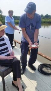 Man showing a fish he caught to an elderly woman