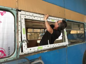 Liniar casement window fit into the side of a vintage bus during a transformation
