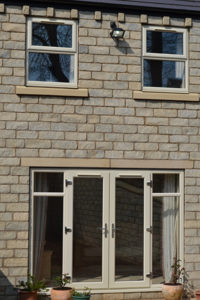 Grey stone building with cream uPVC casement windows and french doors installed by Alternative Windows