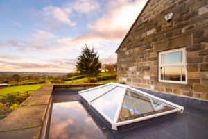 Stone property with an Elevate lantern roof installed under a cloudy yet blue sky